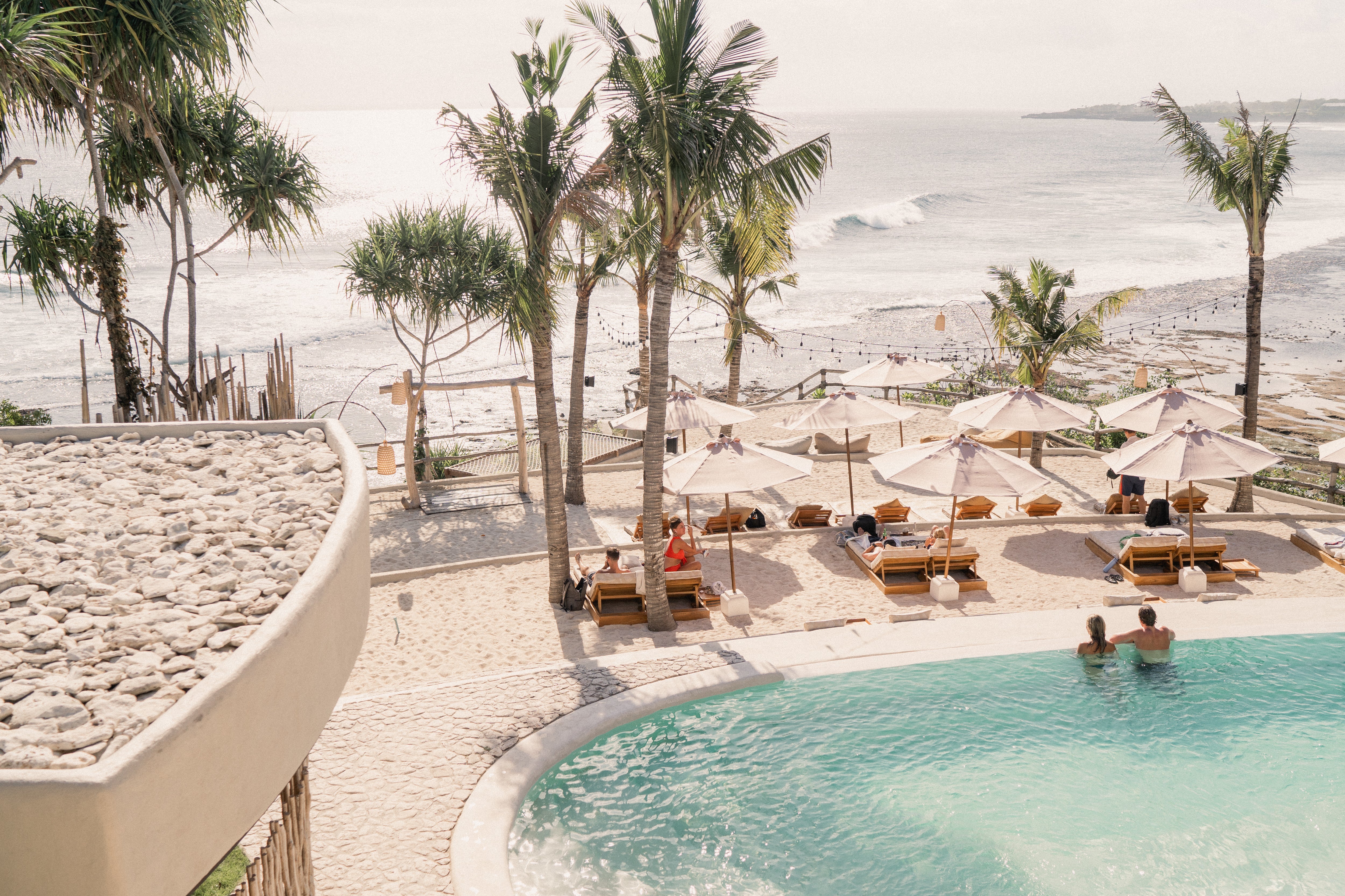 a pool with umbrellas and chairs and palm trees