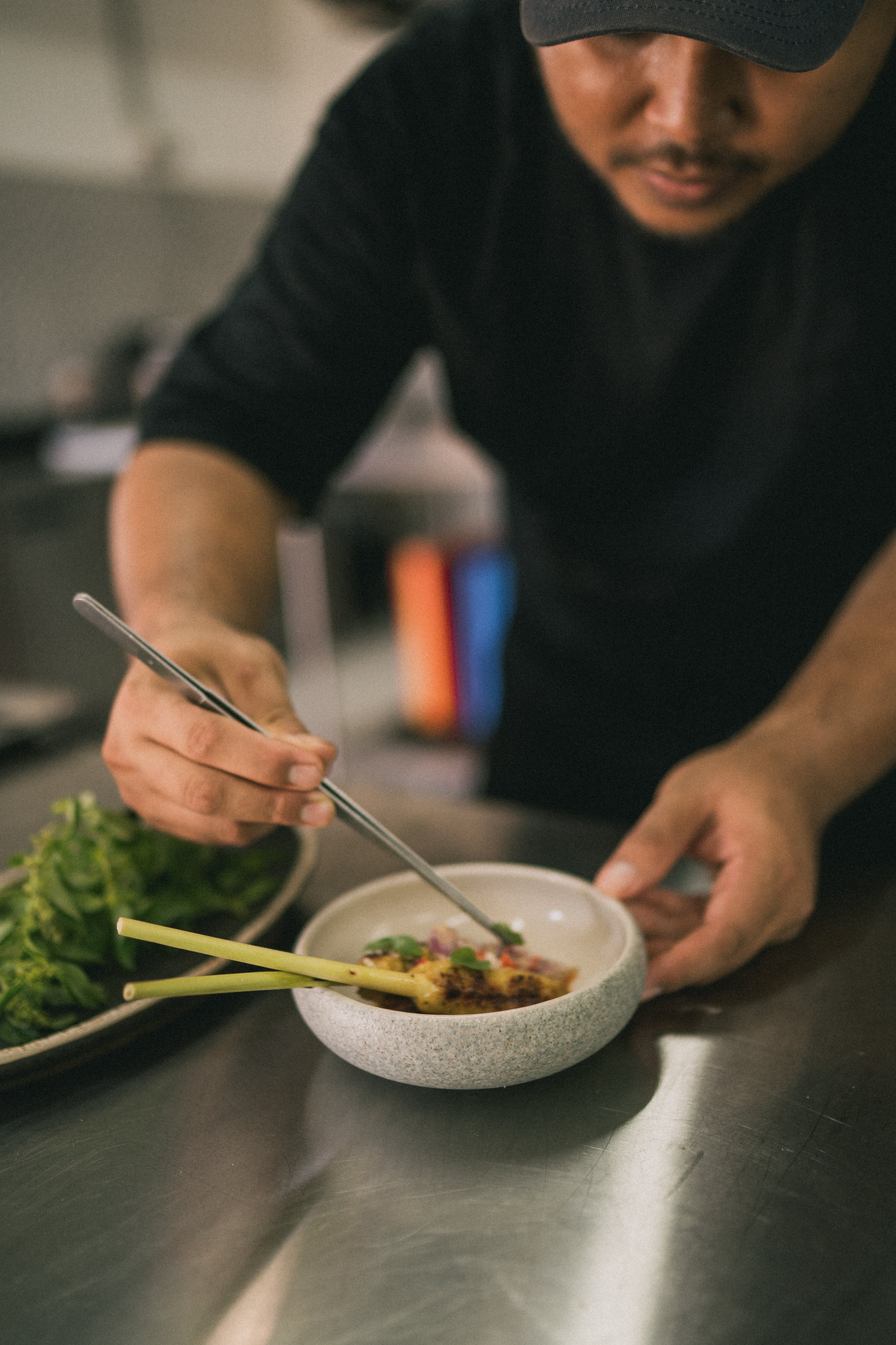 Chef plating a dish with lemongrass in a bowl.