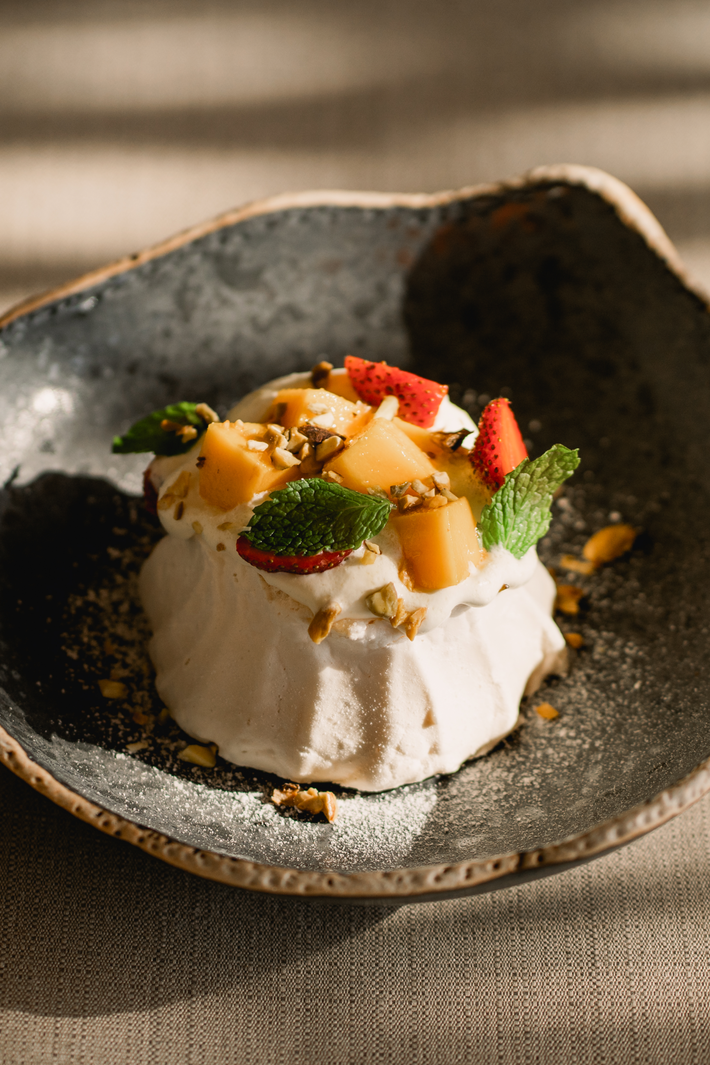  A dessert on a plate with sliced fruit and fresh mint leaves.